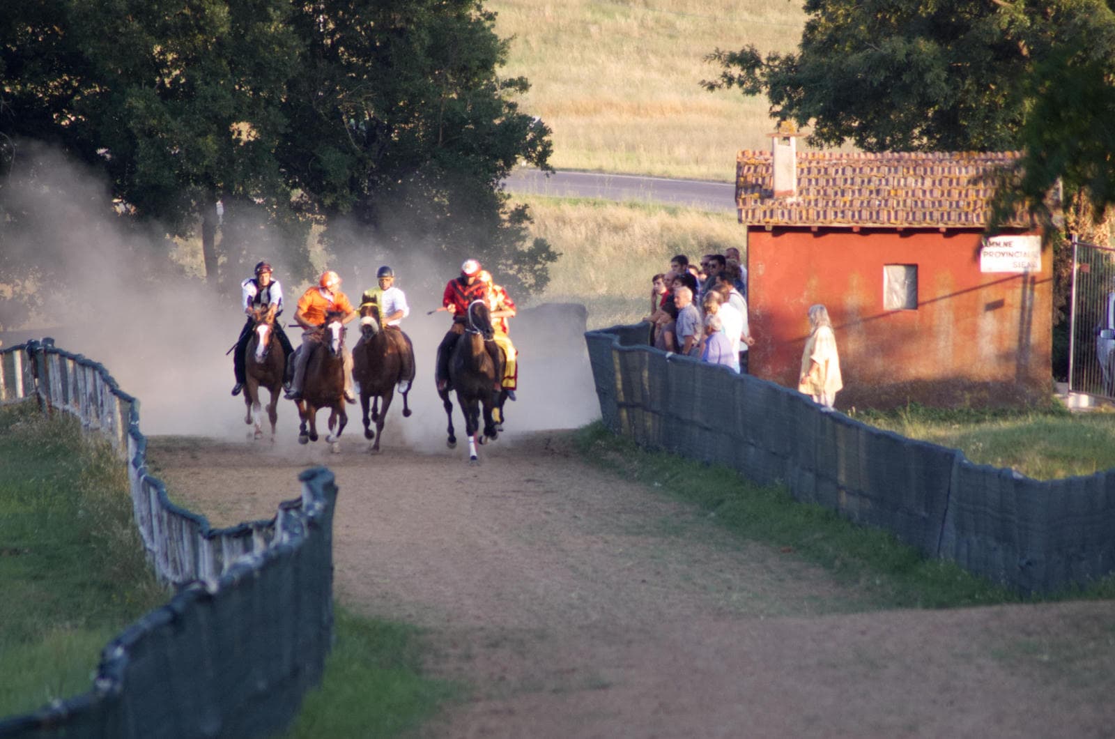 The horses and jockeys race bareback up a gravel track below the village, each one competing to win the 'Palio' for their own village/ palio-casole-race